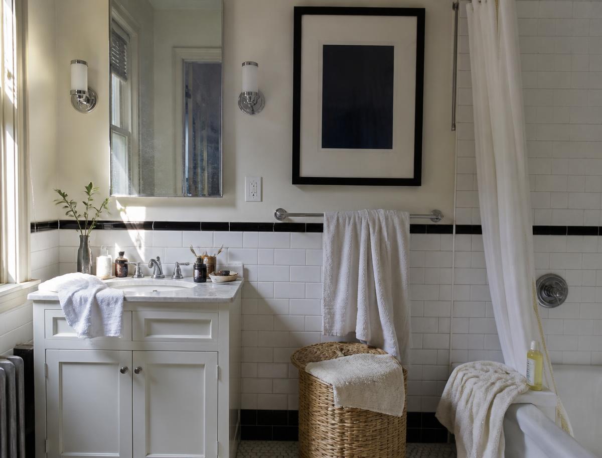 Pre-war NYC bathroom before cleaning, with towels draped and toiletries scattered