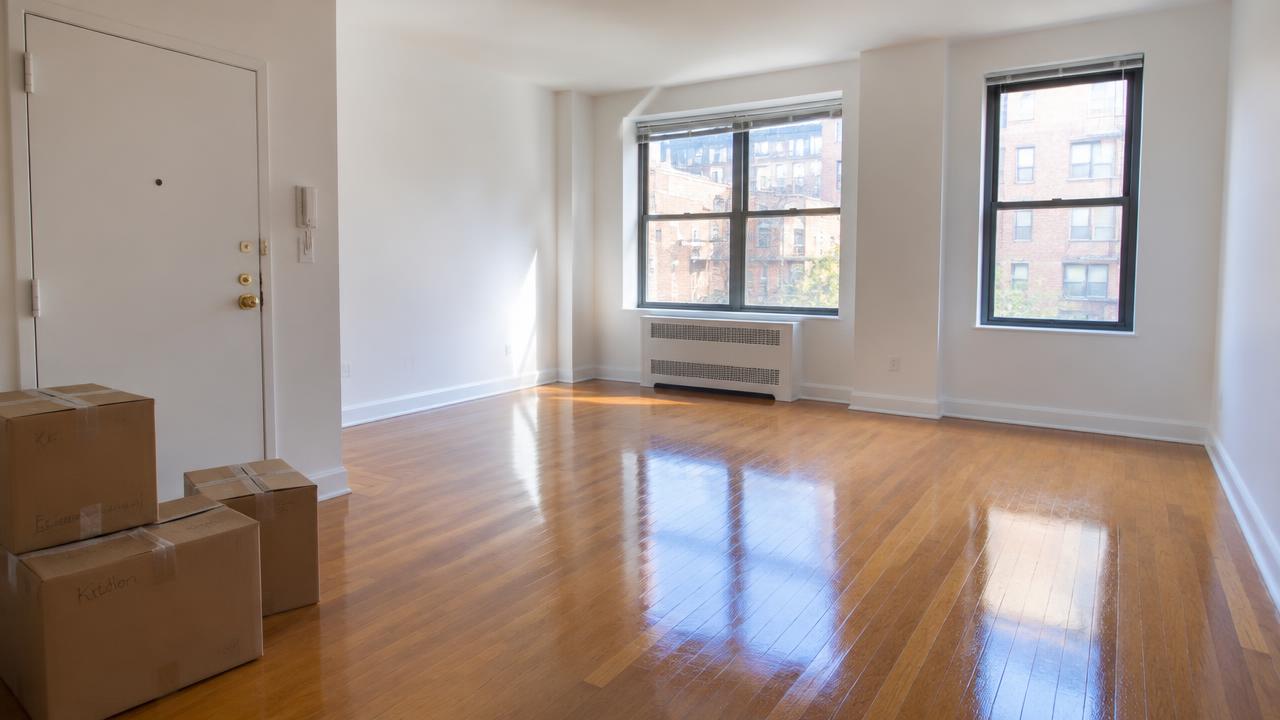 Empty, freshly cleaned NYC apartment with moving boxes by the door
